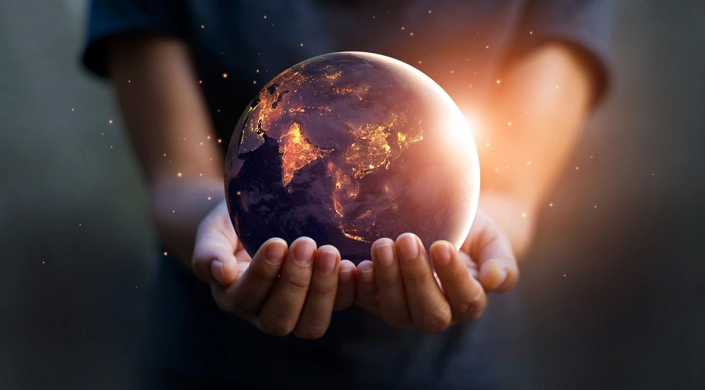 Hands holding a glowing Earth at night.