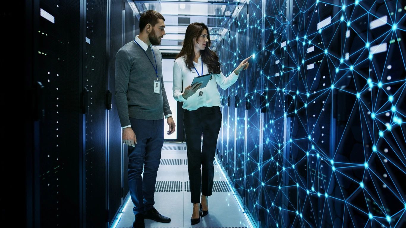 Two IT professionals discussing data in a server room.